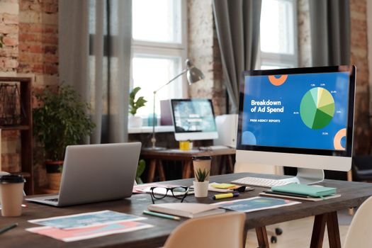 A modern office workspace featuring computers, charts, and office supplies for a productive environment.